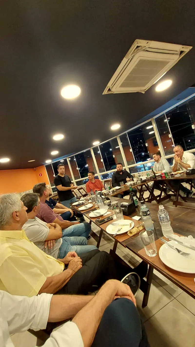 Convidados sentados à mesa longa num evento no salão